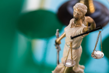 Lady justice statue scales sword green backdrop
